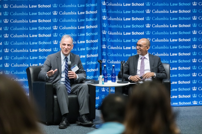 Judge Joseph Bianco in a suit and tie and Columbia Law Dean Daniel Abebe in suit and tie seated at armchairs before a blue Columbia Law School banner