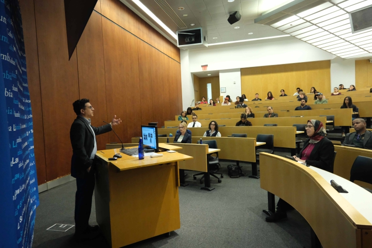 Aziz Rana, Boston College Law School, speaks at a podium in a lecture hall.