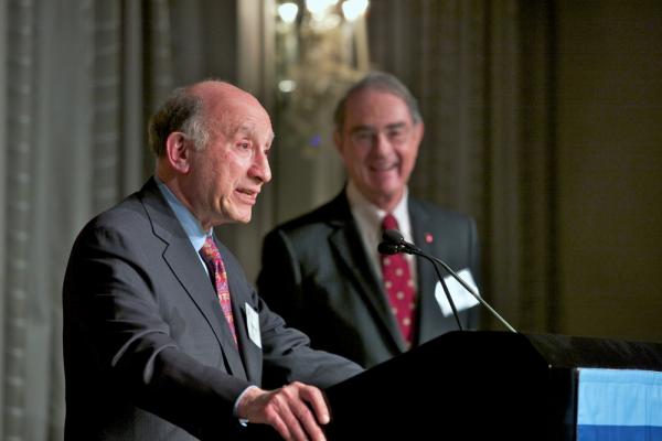 Man in suit and tie stands at a podium