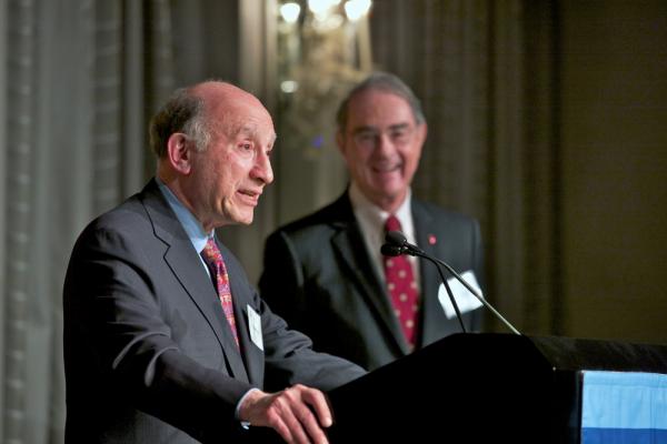 Man in suit and tie stands at a podium