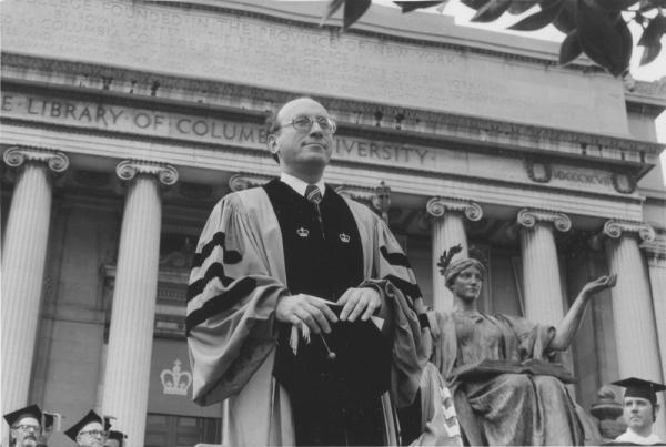 Man standing infront of classical building in commencement robes