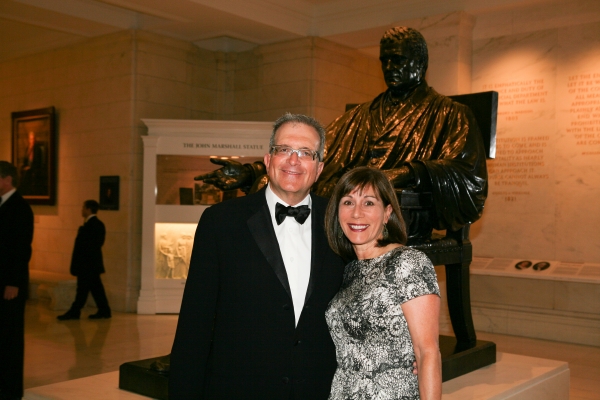 Alumni at the Supreme Court gala pose in front of a statue