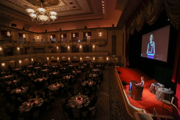 The Waldorf Astoria hosts the Winter Luncheon; a floor of tables in from of a stage.