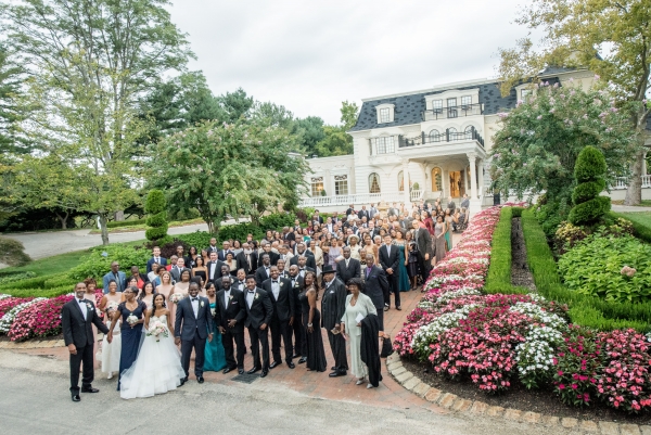 All 175 guests at a wedding outside a mansion surrounded by flowers