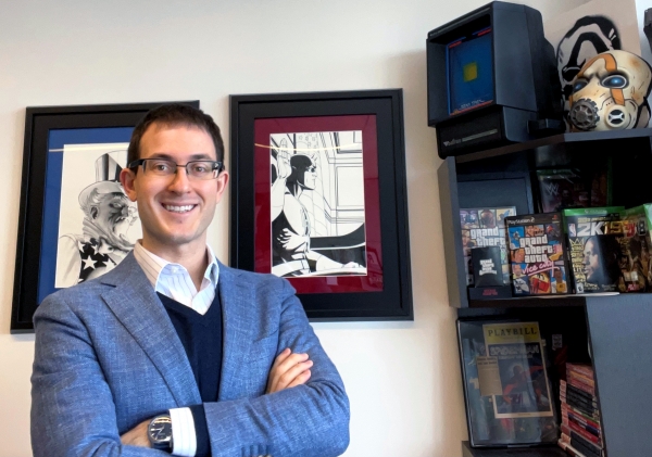 Joshua Simmons in glasses and blue blazer next to bookshelf with memorabilia from his court cases