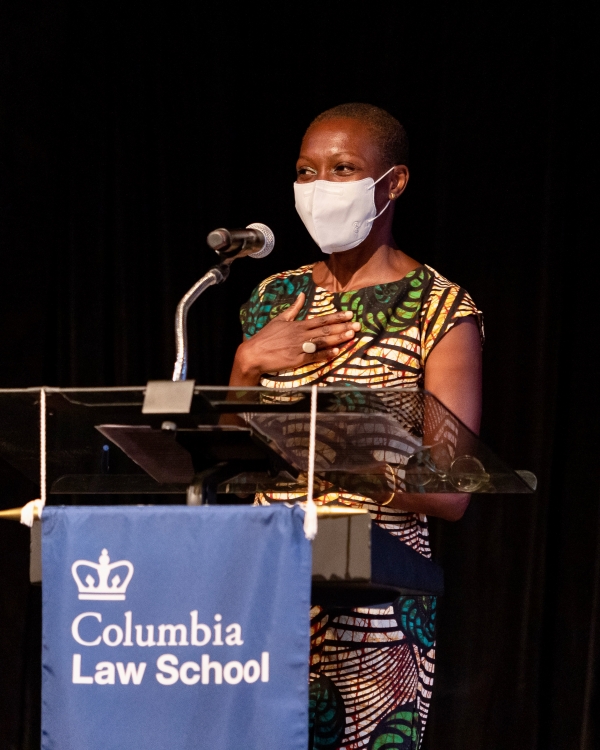 Woman in mask and print dress in front of Columbia Law School podium