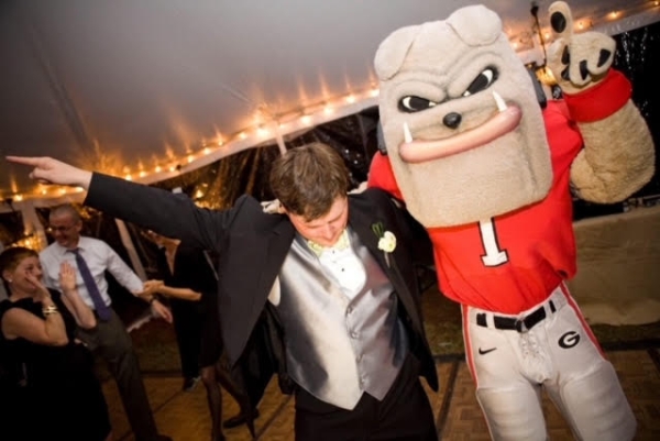 Man in tuxedo dancing with bulldog mascot in football uniform