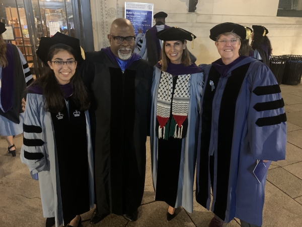 4 students and professors in graduation regalia