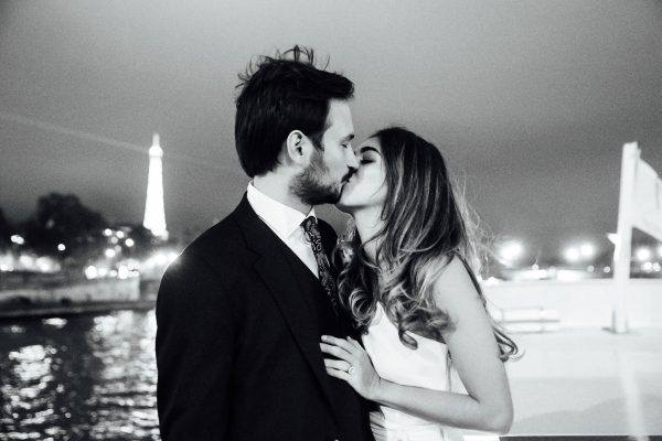 Man and woman kissing on the Seine river in Paris at night