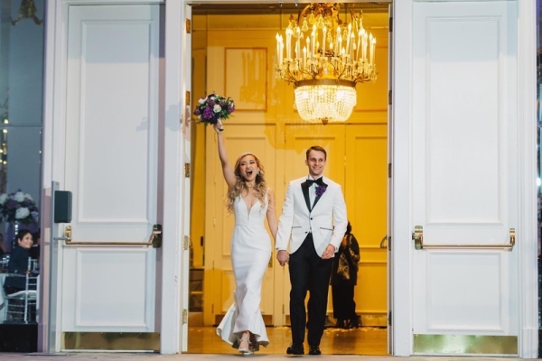 Bride with bouquet and groom arriving in a ballroom