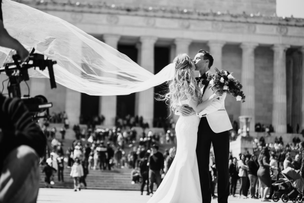 Bride and groom kiss in front of the columns of the Lincoln Memorial