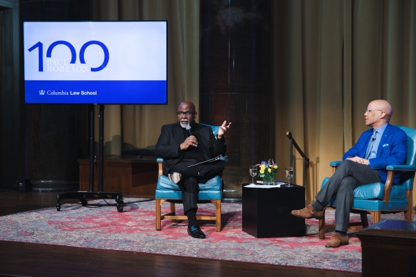 two men sitting on chairs on a stage