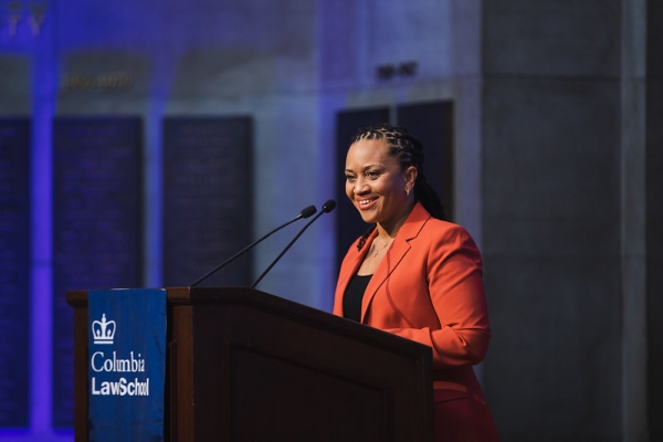 Woman in orange jacket at lectern