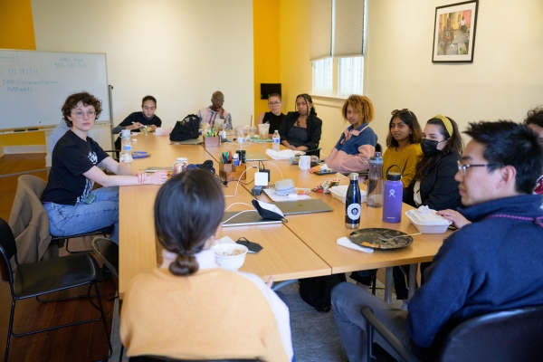 Students seated around conference table listening to speaker