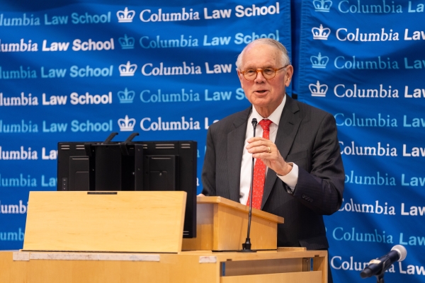 Man in jacket and red tie at podium