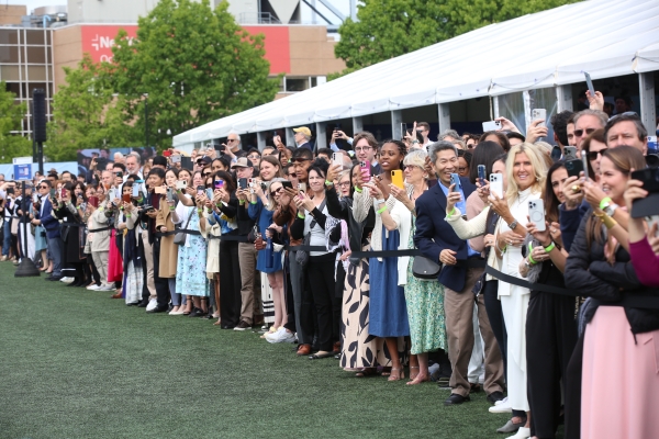 Crowd of people with cameras lined up behind rope