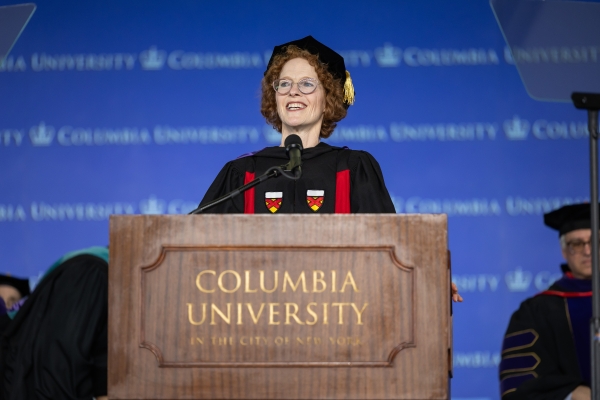 Woman in academic regalia speaks at podium