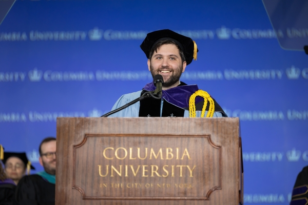 Bearded man in tam and robe at podium