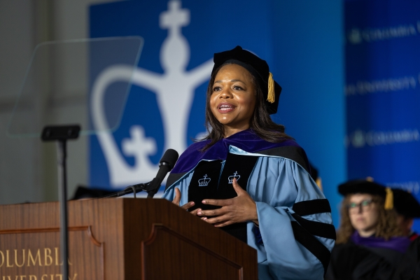 Woman in tam and academic regalia speaks at podium