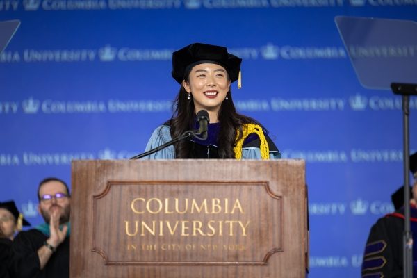 Dark haired woman in tam and robe at podium