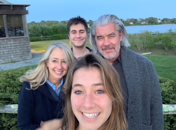 Am outdoor photo of Amanda Moretti and Greg Lee with their adult son and daughter on a lawn with the sea in the background
