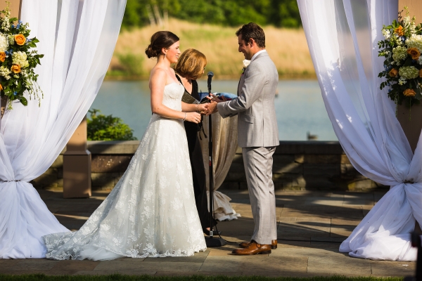 Katherine Solomon in a white wedding dress exchanging vows with Jared Solomon beneath a canopy outdoors.