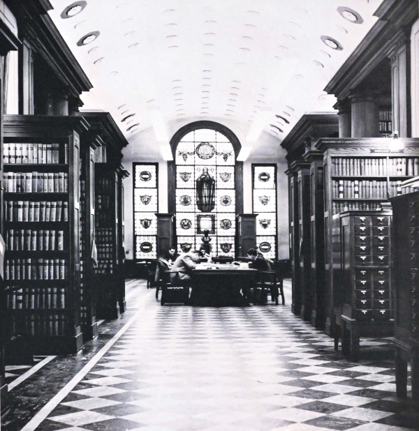 Black and white photo Kent Hall Library view of stained glass window with wood bookcases framing the view