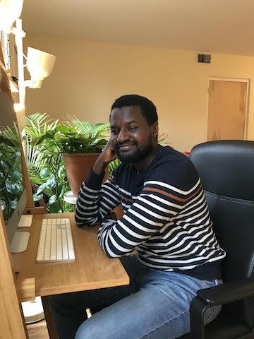 Columbia Law student Ibrahim Diallo in a striped sweater sitting in front of a computer