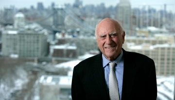 Jack Weinstein portrait, smiling in front of a cityscape