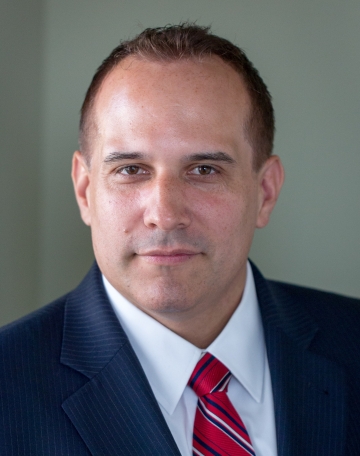 Headshot of man in suit with red striped tie