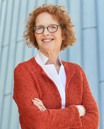 Dean Gillian Lester smiling while wearing an orange jacket