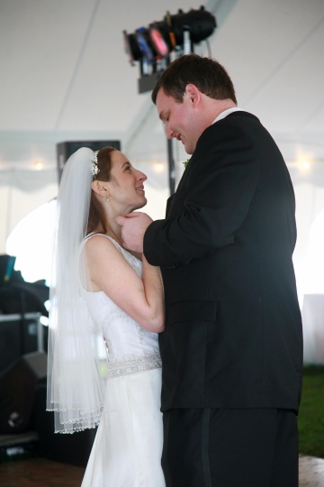 Bride in veil dancing with her much taller husband.