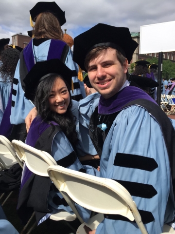 A woman and man in graduation robes outdoors at Columbia University
