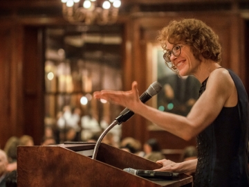 Woman in sleeveless dress in front of microphone at podium