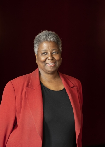 Woman with short gray curls wearing red jacket