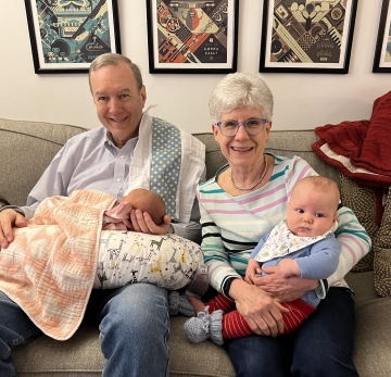 A grandfather and grandmother holding babies.
