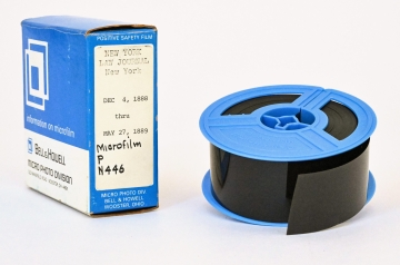 Blue and white microfilm box and blue reel of microfilm