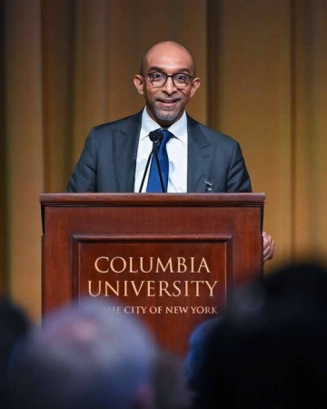 Dean Daniel Abebe in tie and jacket before a wood podium that says Columbia University